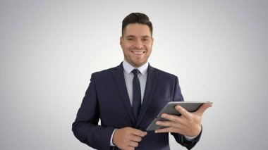 Tabletten sayfalar aşıran ve kameraya gülümseyen yakışıklı bir adam.