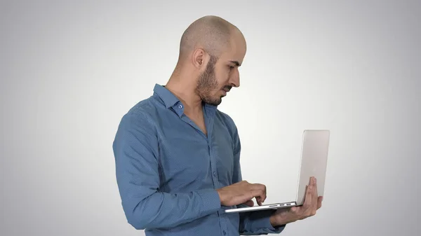 Giovane uomo d'affari mediorientale, in piedi e digitando sul computer portatile — Foto Stock