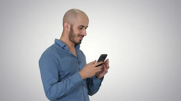 Casual árabe hombre de negocios usando el teléfono y sonriendo en gradien — Foto de Stock