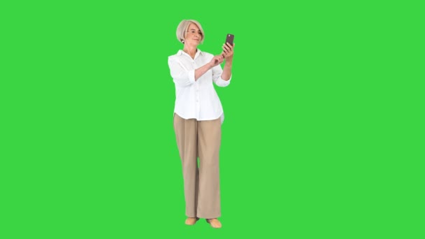 Inteligente abuela tomando una selfie en una pantalla verde, Clave de croma. — Vídeos de Stock