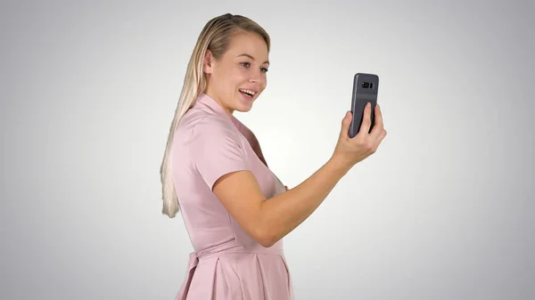 Female in pink dress making video call with her smart phone on g — Stock Photo, Image