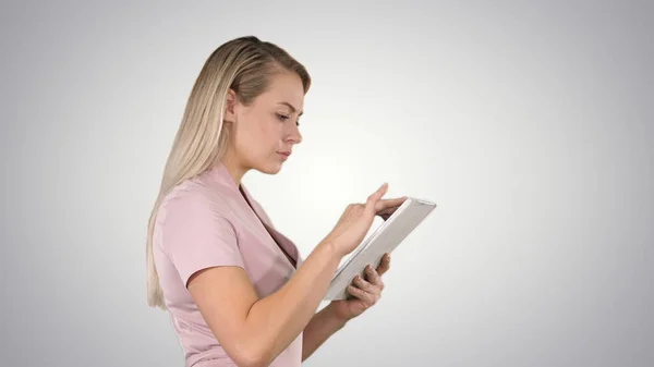Dziewczyna trzyma cyfrowy tablet szukając czegoś na gradiencie — Zdjęcie stockowe