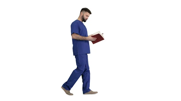 Doctor reading medical journal while walking on white background — Stock Photo, Image