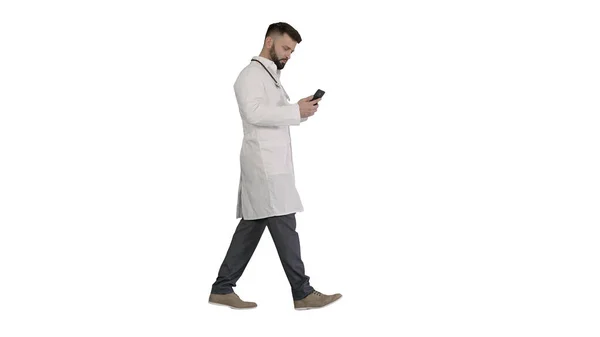 Médecin masculin en uniforme médical blanc marchant et utilisant smartphon — Photo