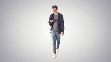 Günlük kıyafetli genç adam cep telefonundan mesaj atıyor.