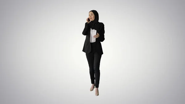 Atractiva mujer musulmana moderna caminando y hablando por teléfono celular —  Fotos de Stock