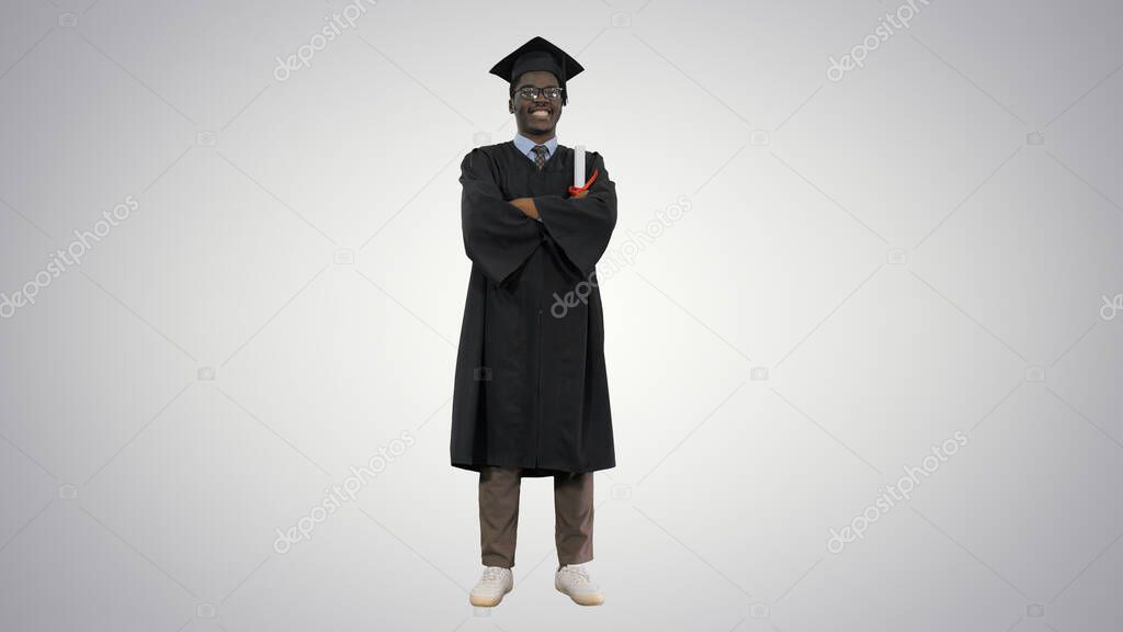 African american male student in graduation robe folding arms wi