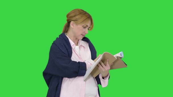 Mujer rubia embarazada leyendo revista en una pantalla verde, Chroma Key. — Vídeo de stock