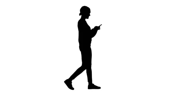 Silhouette Pretty young female texting on mobile phone while wal — Stock Photo, Image