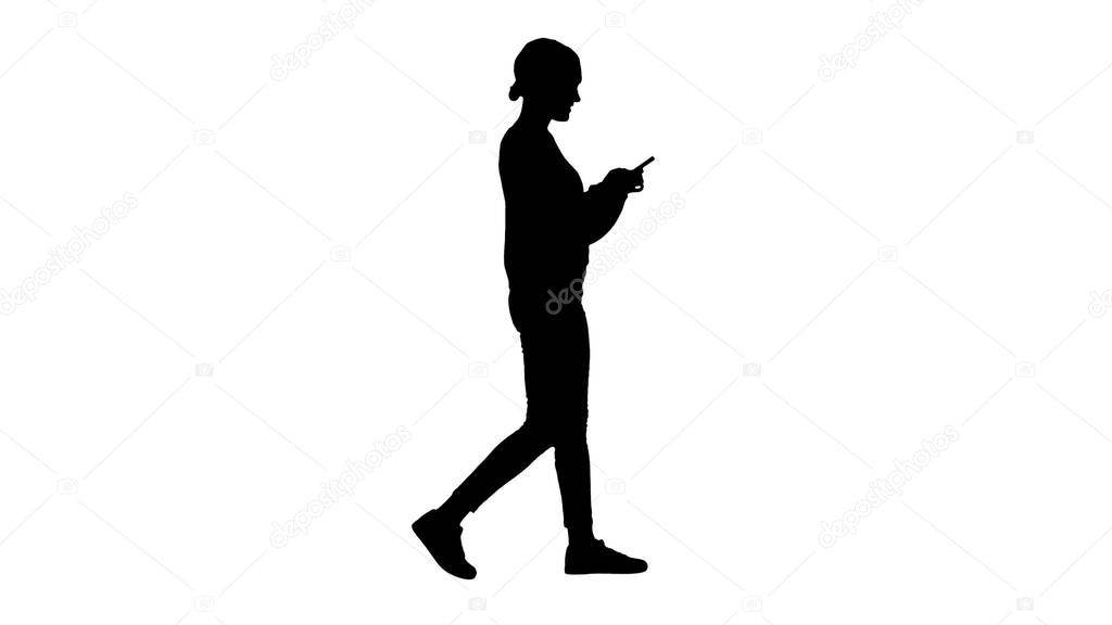Silhouette Pretty young female texting on mobile phone while wal