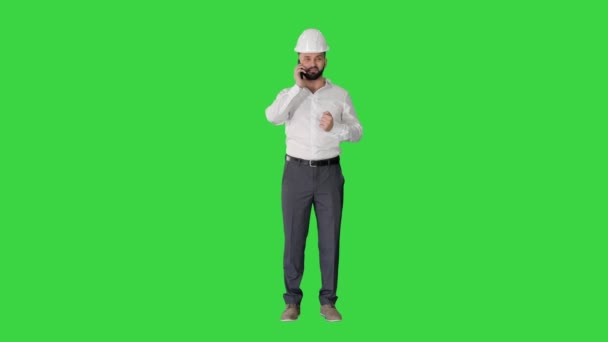 Ingenieur mit weißer Mütze im Gespräch mit seinem Handy auf einem Green Screen, Chroma Key. — Stockvideo