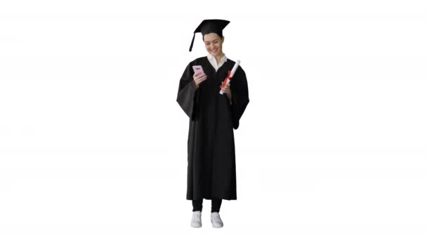 Diploması olan mutlu bir bayan mezun ve beyaz arka planda telefonuyla mesajlaşıyor.. — Stok video