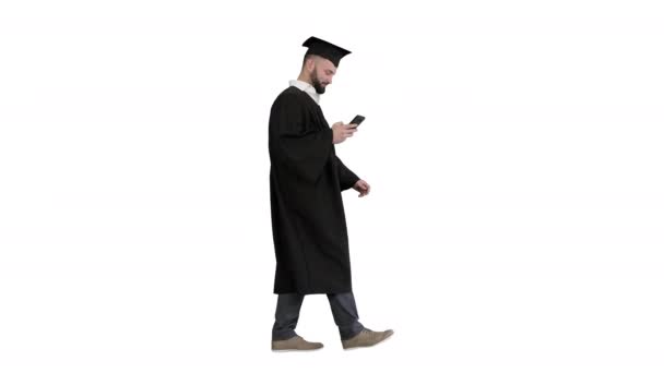 Graduate student walking and texting message on the phone on white background. — Vídeo de Stock