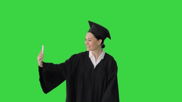 Feliz graduada femenina en mortero haciendo selfie en su teléfono en una pantalla verde, Chroma Key. — Vídeos de Stock