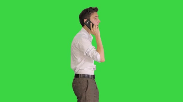 Knappe man met telefoongesprek tijdens het lopen op een groen scherm, Chroma Key. — Stockvideo