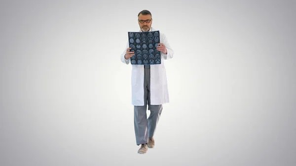 Médico maduro caminando y revisando una resonancia magnética en gradi — Foto de Stock