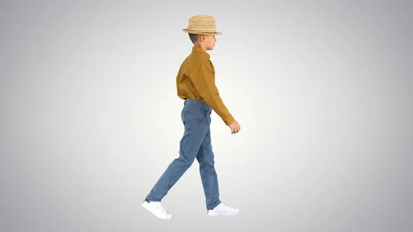 Niño en una camisa ajustando su sombrero de paja mientras camina y mira —  Fotos de Stock