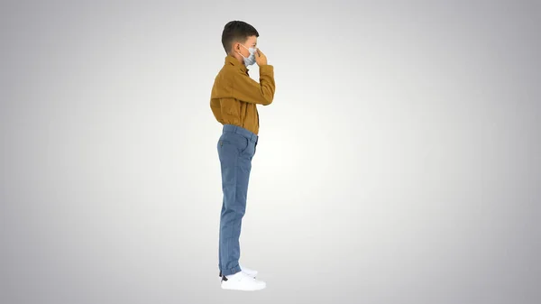 Piccolo ragazzo che regola la sua maschera viso guardando la fotocamera sul gradiente — Foto Stock