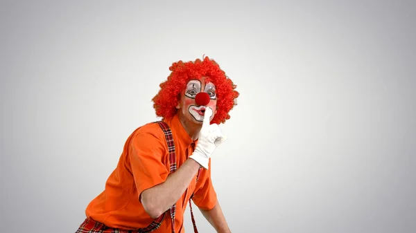 Clown prowling and making be quiet gesture to camera on gradient — Stock Photo, Image