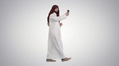 Arap adam yürüyor ve gradyan arka planda telefonuyla selfie çekiyor..
