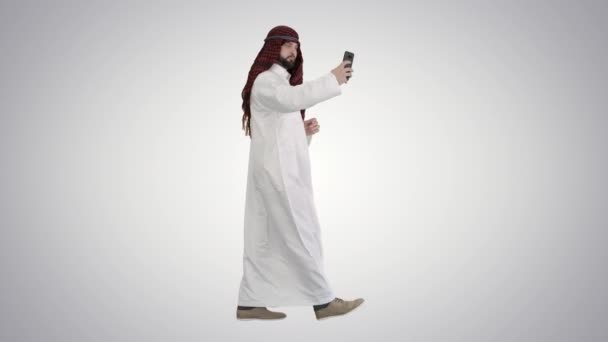 在渐变背景下，阿拉伯男人一边走路一边用手机自拍. — 图库视频影像