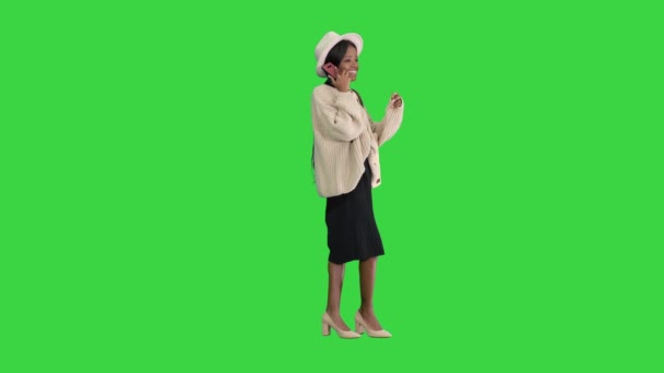Улыбающаяся африканская американка в трикотаже и шляпе разговаривает по телефону на зеленом экране, Chroma Key. — стоковое видео