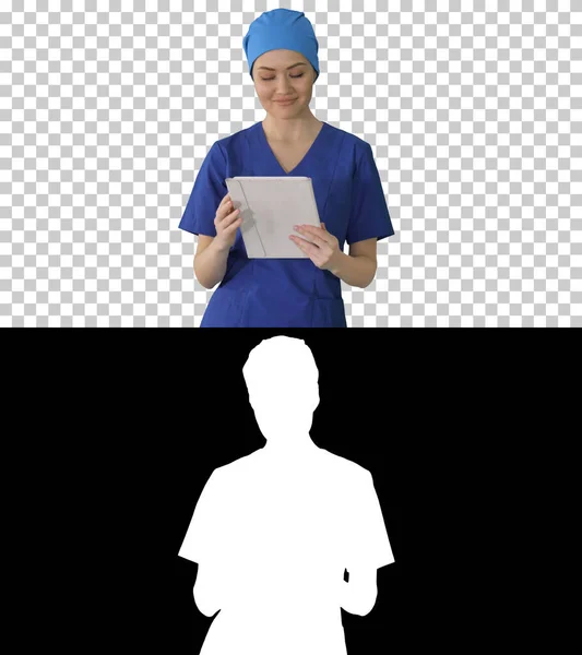Smiling female nurse using tablet computer walking and looking a