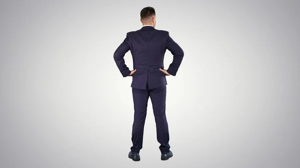 Бизнесмен смотрит вокруг с руками на бедра на градиент backgr — стоковое фото