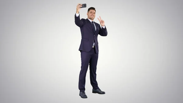 Hombre de negocios tomando selfie en el fondo gradiente. — Foto de Stock