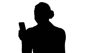 Siluet Genç kız cep telefonu ekranından okuyor.