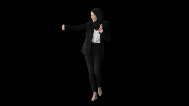 ヒジャーブのアラブ人女性を笑顔で歩きながら携帯電話で自撮りアルファチャンネル — ストック動画