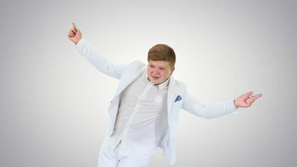 グラデーションの背景で踊る白いスーツの少年. — ストック写真