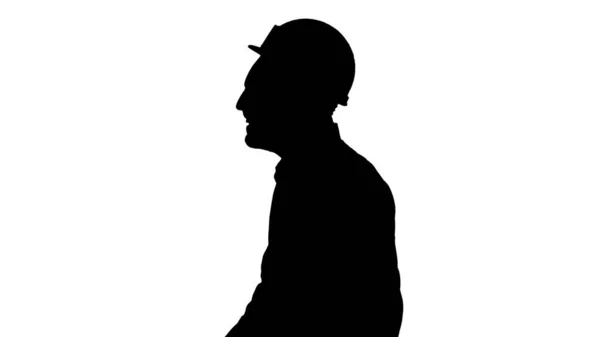 Силуэт Улыбающийся инженер-строитель, ловящий шапку и удар — стоковое фото