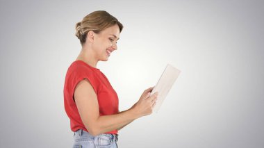 Dijital tablet kullanan sıradan giyinmiş bir kadın gradien üzerinde yürüyor