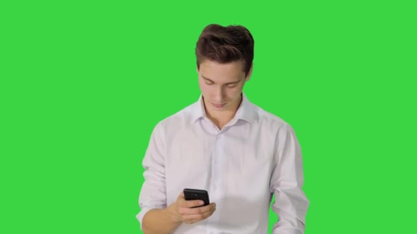 Άνδρας με λευκό πουκάμισο που περπατά χρησιμοποιώντας το κινητό τηλέφωνο σε μια πράσινη οθόνη, Chroma Key. — Αρχείο Βίντεο