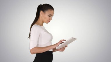 Çekici iş kadını yürürken dijital tablet kullanıyor.