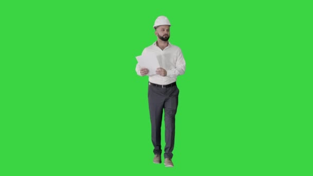 Männlicher Bauunternehmer Ingenieur mit festem Hut zu Fuß, Blick auf Objekt und in Papiere, Dokumente auf einem Green Screen, Chroma Key. — Stockvideo