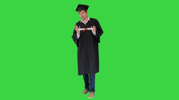 Mężczyzna student w ukończeniu studiów szlafrok pokazując jego dyplom na zielony ekran, Chroma klucz. — Wideo stockowe