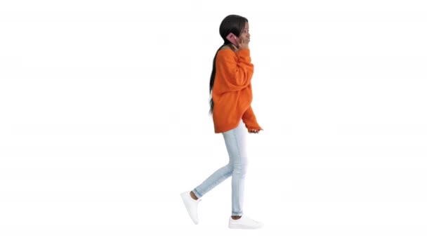 Emocionální africký Američan žena v jasném jumper mluvit na telefonu při chůzi na bílém pozadí. — Stock video