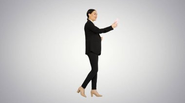 Takım elbiseli genç bir kadın telefonunda iş videosu var.