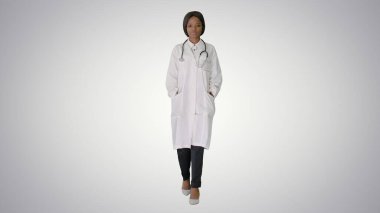 Üzgün Afrikalı Amerikalı kadın doktor elleri cebinde yürüyor.