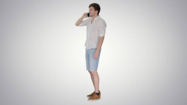 Mutlu genç adam cep telefonuyla konuşuyor ve gradyanda gülümsüyor.