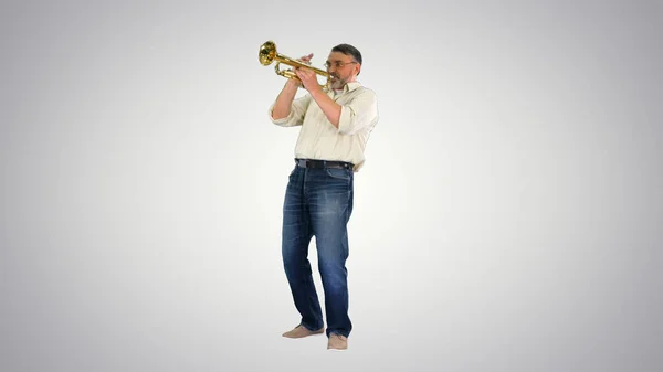 Старший музикант грає на трубі на градієнтному фоні . — стокове фото