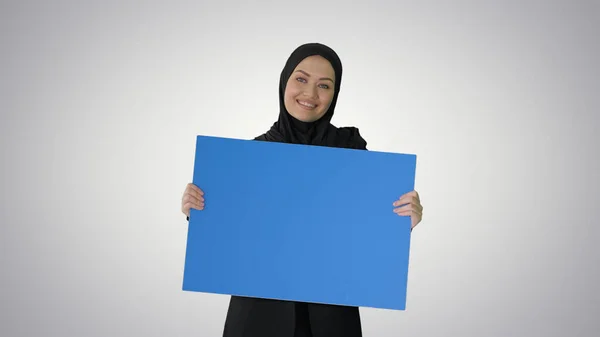 Lächelnde Araberin im Hijab mit blauem Plakat und Blick — Stockfoto