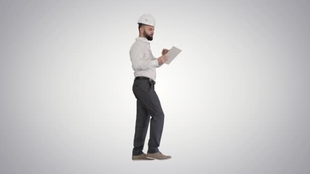 Specialist în construcții folosind un computer tabletă în timp ce mergeți pe fundal gradient . — Videoclip de stoc