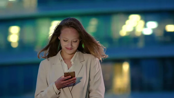 Młoda dziewczyna w nocy czyta wiadomości na smartfonie. — Zdjęcie stockowe