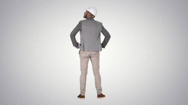 Mühendis, gradyan arka planda duruyor ve etrafa bakıyor.