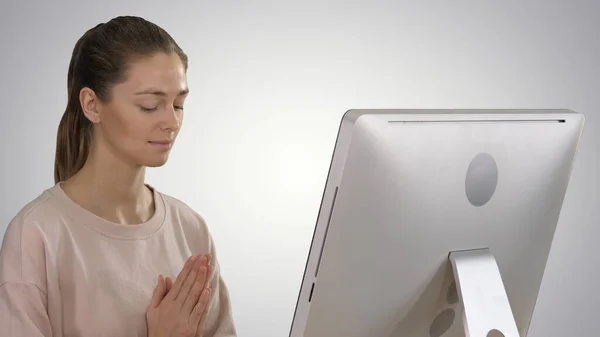 Attractive woman in a chair at the table with computer meditating on gradient background. — Stock Photo, Image