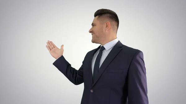 Business man pointing on product and talking to camera on gradie — Stock Photo, Image