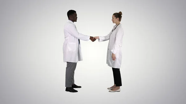두 젊은 의사가 과도 한 배경에 손을 흔들고 있다. — 스톡 사진